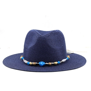Detail of navy fedora straw hat featuring colorful beaded band and wide sun brim