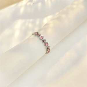 Adjustable silver geometric ring with pink zircon stones on a white stand