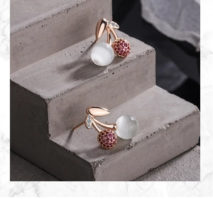 Detail of rose gold cherry stud earrings with opal stone and red crystals on stone