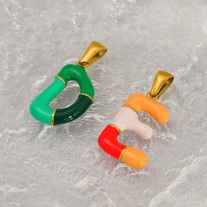 Detailed close-up of colorful enamel letter pendants in green and orange with gold finish