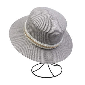 Detail of grey straw sun hat featuring elegant double pearl and gold chain decorations