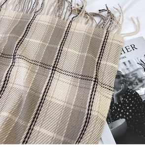 Detailed texture of khaki plaid tassel scarf with soft wool-like woven fabric