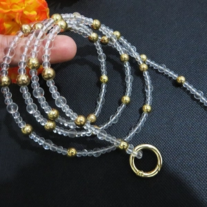 Detail of beaded bag strap featuring clear resin beads and gold metal accents with spring clasp