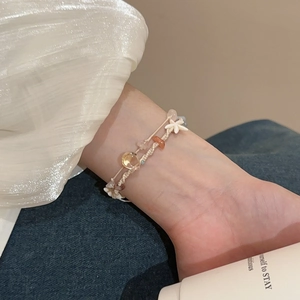 Detail eines handgewebten Armbands mit Seestern-Anhänger und bunten Steinperlen am Handgelenk