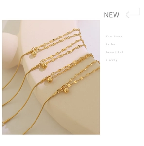 Detail of gold double-layer chain with small steel ball pendant on minimalist stand