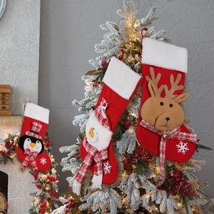 Knitted Christmas stockings with reindeer, snowman and penguin patterns on festive tree