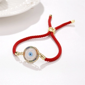 Dettaglio del ciondolo occhio del diavolo dorato su bracciale intrecciato rosso