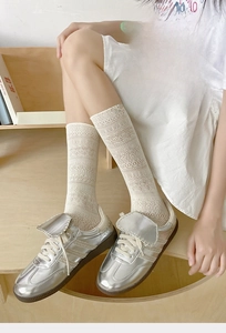 Close-up of cream lace calf socks with hollow wavy knit pattern and retro sneakers