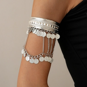 Detailed shot of silver coin tassel arm bracelet with bohemian pyramid textures on model