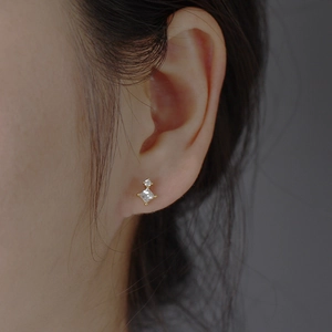 Macro shot of gold geometric earrings with square zircon pendant for women