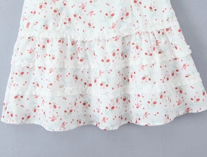 Detalle de falda floral con capas múltiples y bordes de encaje blanco en el dobladillo