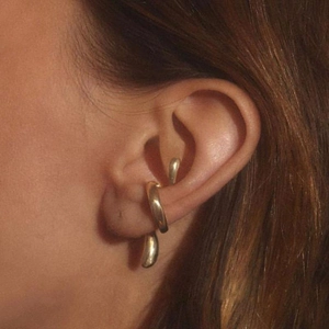 Close-up of a minimalist gold teardrop earring and ear cuff set worn on a model ear