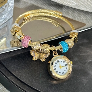 Macro detail of golden charm bracelet watch with crystal beads and butterfly pendant