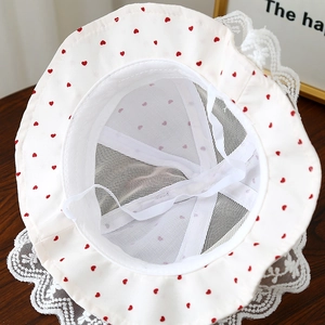 Détail chapeau de soleil bébé avec motifs cœurs rouges, dentelle et doublure en maille