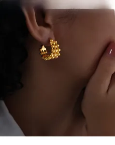 Detail showing the textured 18K gold-plated C-shape hoop earrings worn by a model