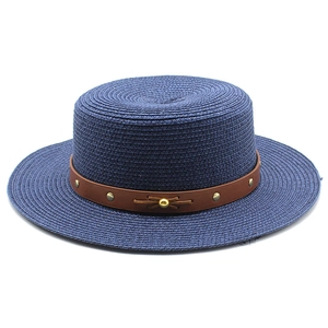 Détail d'un chapeau de paille bleu marine avec ruban cuir et rivets dorés