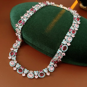 Détail d'un collier vintage en argent avec pierres roses et rouges sur velours