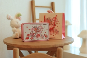 Tin gift box set with bunny illustration and matching paper bag on wooden table