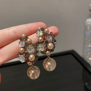 Elegant drop earrings featuring large teardrop pearls, champagne crystals, and floral accents