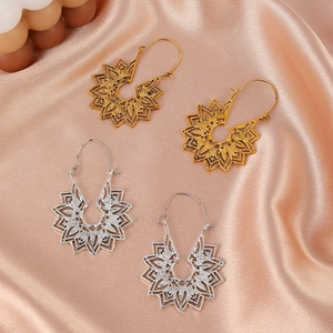 Macro de boucles d'oreilles fleurs évidées or et argent sur tissu en soie champagne