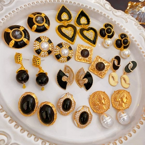 Flat lay of vintage style flower earrings with pearls and black enamel on a white plate