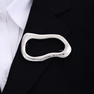Polished silver irregular oval brooch pinned on a black suit blazer for a sleek look