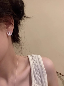 Detail of a silver twisted heart-shaped stud earring shown worn on a model's ear