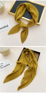 Detailed view of ginger yellow pleated scarf with fine accordion folds and soft texture