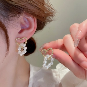 Elegant gold heart earrings with pearl drop detail shown on a person for women
