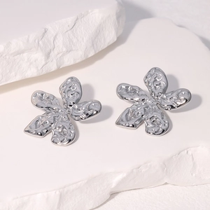 Close-up of silver five-petal flower stud earrings with molten metal texture on stone