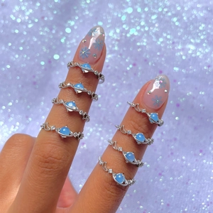Detail shot of silver planet rings with blue Saturn charm on a hand with snowflake nail art