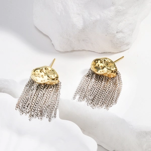 Détail de boucles d'oreilles à pompons avec clous dorés sur pierre blanche