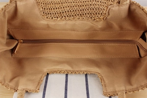 Macro detail of straw shoulder bag interior with khaki fabric lining and zipper pocket