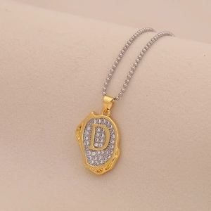 Detail of two-tone irregular pendant necklace with crystal letter D and silver bead chain