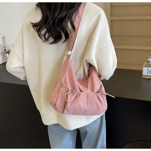 Detailed back view of pink nylon crossbody bag with drawstring and wide strap on model