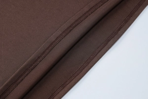 Vue détaillée de l'ourlet de la robe marron avec double couture et texture du tissu de qualité