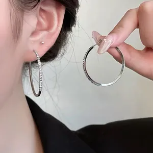 Macro detail of large silver hoop earrings featuring sparkling white zircon stone inlay