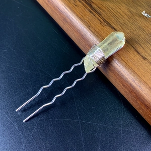 Close-up of yellow natural crystal U-shaped hairpin with silver wavy metal pins