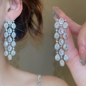 Macro shot of sparkling silver flower tassel earrings with zircons on model's ear