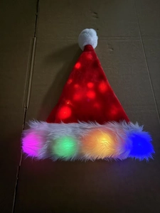 Detail of red plush Santa hat with integrated colorful LED lights and white trim