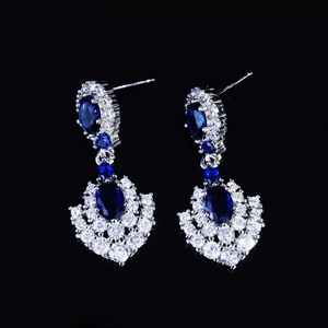 Detailed close-up of royal blue sapphire earrings with white zircon on black background