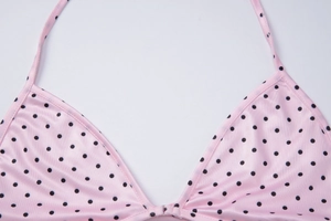 Detail of pink bikini top with black polka dots featuring silky fabric and premium texture