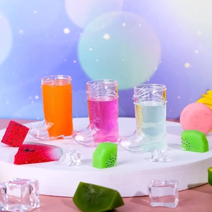 Cowboy boot plastic shot glasses filled with colorful drinks on a platform with ice