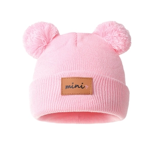 Pink winter knit baby hat with cute double pompoms and mini leather patch detail