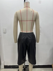 Detail view of the back of black faux leather shorts featuring rear welt pockets