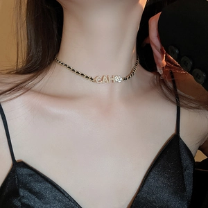 Close-up of a gold choker featuring zircon letter pendants and a camellia flower