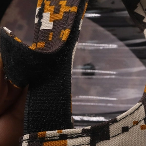 Macro view of digital camouflage fabric and adjustable black hook and loop strap closure