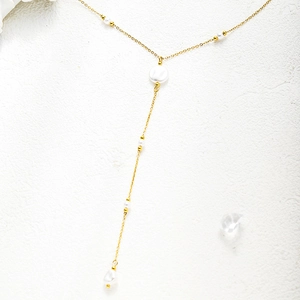 Detailed view of elegant gold-plated tassel necklace with multiple white pearls on white background