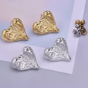 Macro detail of heart-shaped earrings in gold and silver with textured metal surface
