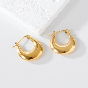 Close-up of chunky gold minimalist earrings on a white stone background